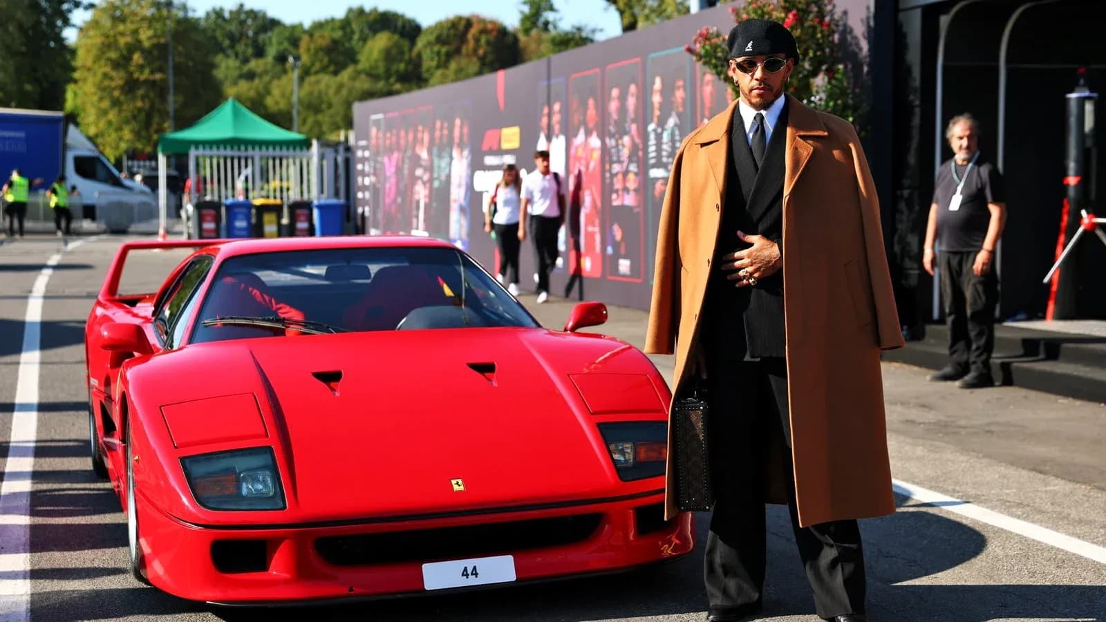 Man in stylish coat beside red sports car Man in stylish coat beside red sports car