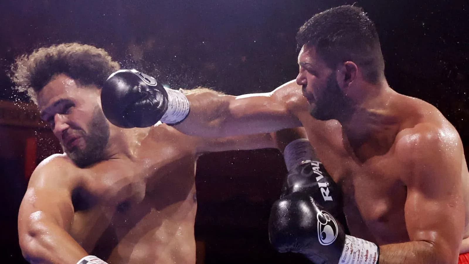 Two boxers engaged in a match, one delivering a punch Two boxers engaged in a match, one delivering a punch