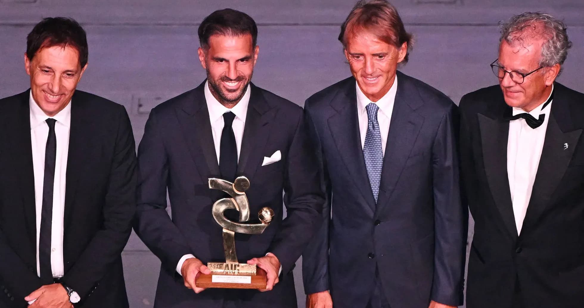 Group of four men holding an award at event Group of four men holding an award at event