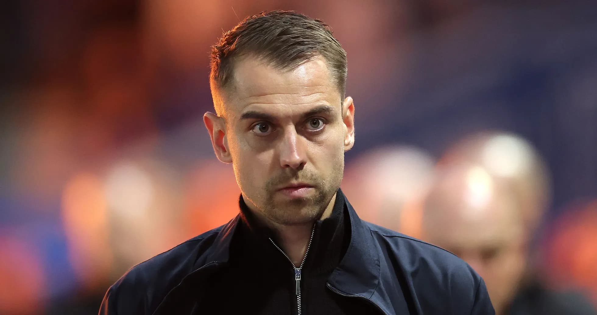 Man in jacket walking on sidelines during match Man in jacket walking on sidelines during match