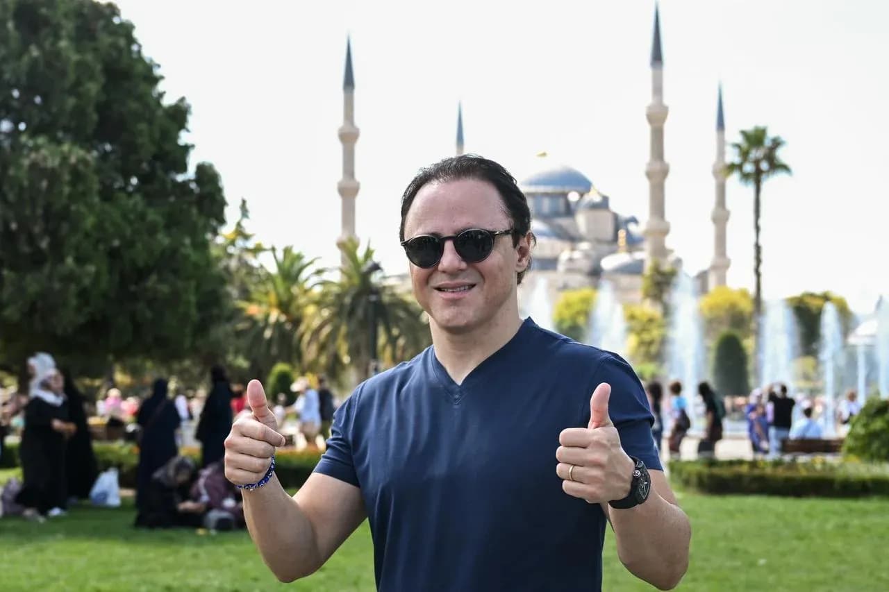 Person giving thumbs up in front of mosque Person giving thumbs up in front of mosque