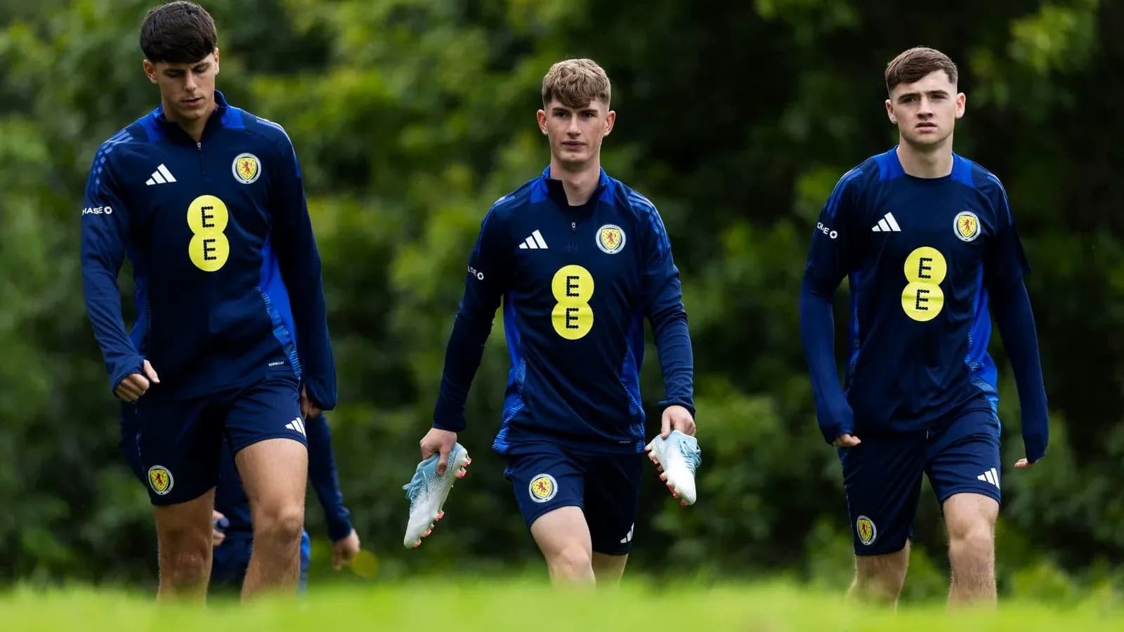 Three players walking in training kits with football boots Three players walking in training kits with football boots