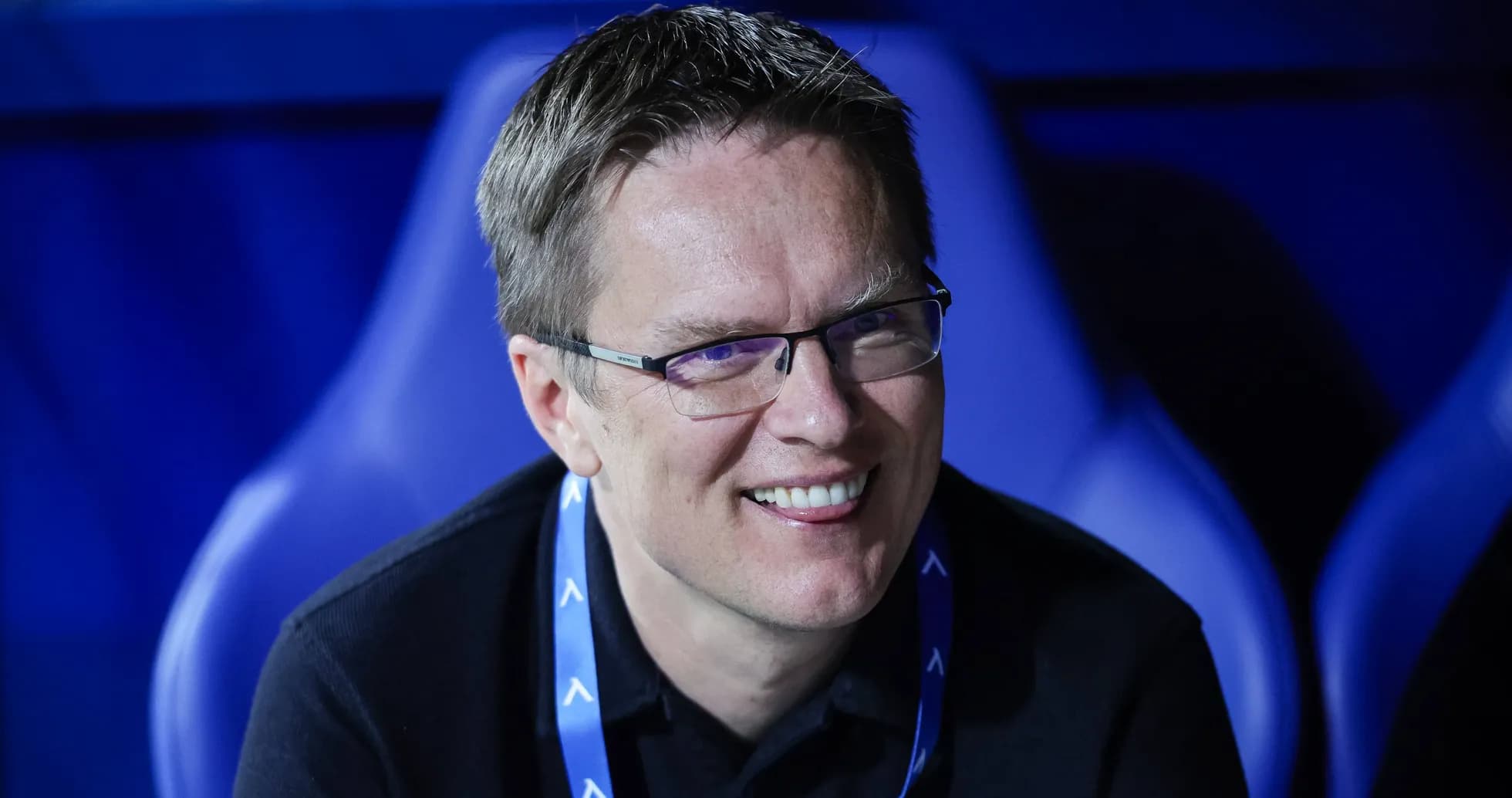Man smiling while seated in a sports venue Man smiling while seated in a sports venue