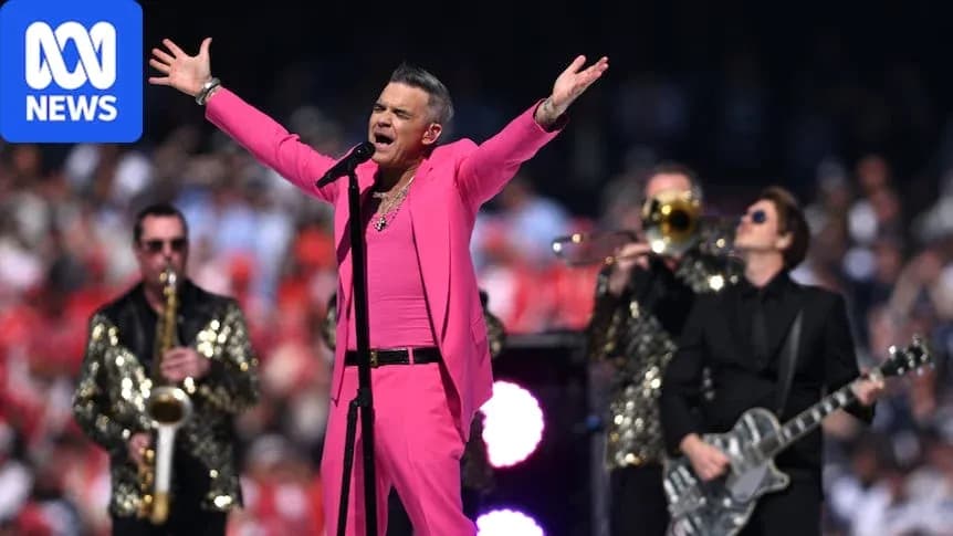 Robbie Williams performing on stage in pink outfit Robbie Williams performing on stage in pink outfit