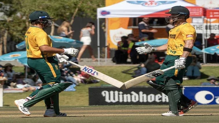 Two cricket players exchanging bats during match Two cricket players exchanging bats during match